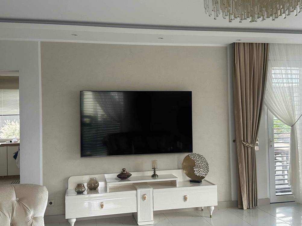 Ein 80-Zoll-Fernseher ist zum Testen in einem großen Raum an der Wand über einem Sideboard aufgehängt.