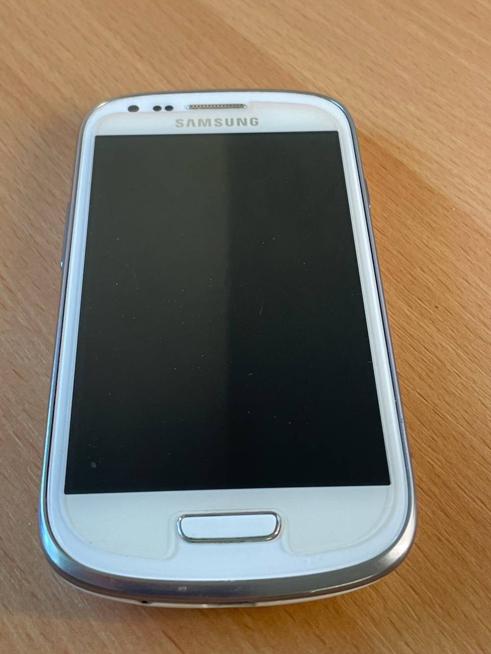 Ein Samsung-Handy bis 300 Euro im Test auf einer Holzfläche liegend.