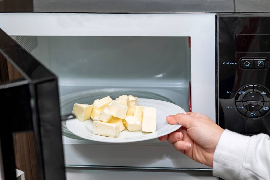 Samsung-Mikrowelle-Test: Nahaufnahme einer weiblichen Hand, die Butter in der Mikrowelle auf einem weißen Teller schmilzt. 