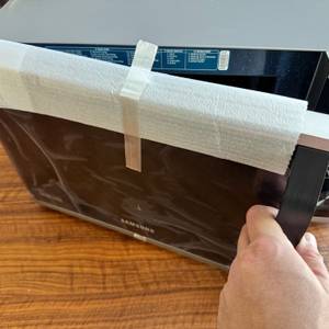 Eine Hand öffnet die verpackte Tür der Samsung MW3500K