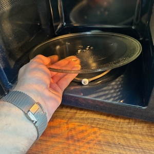 Eine Hand entnimmt den Drehteller der Samsung MW3500K