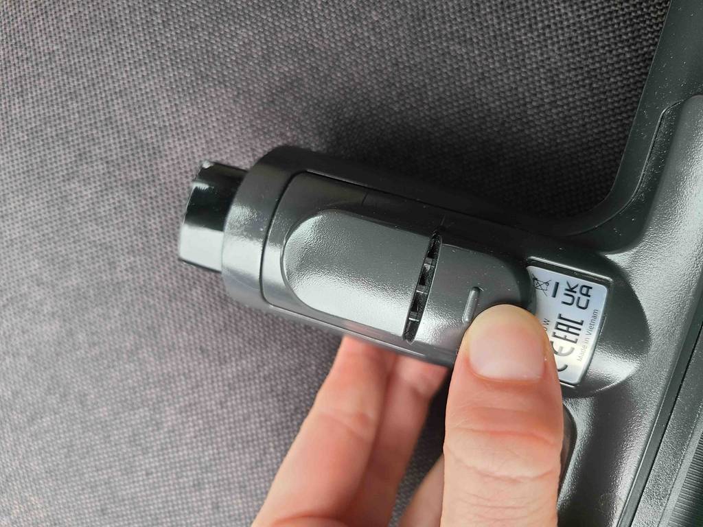 Eine Hand betätigt den Clickverschluss einer getesteten Staubsauger-Tierhaarbürste.