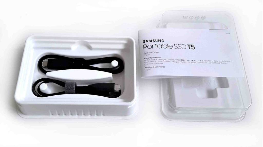 Externe SSD-Festplatten im Test: zwei USB-Anschlusskabel in der geöffneten Originalverpackung inklusive Gebrauchsanweisung auf einer weißen Oberfläche.