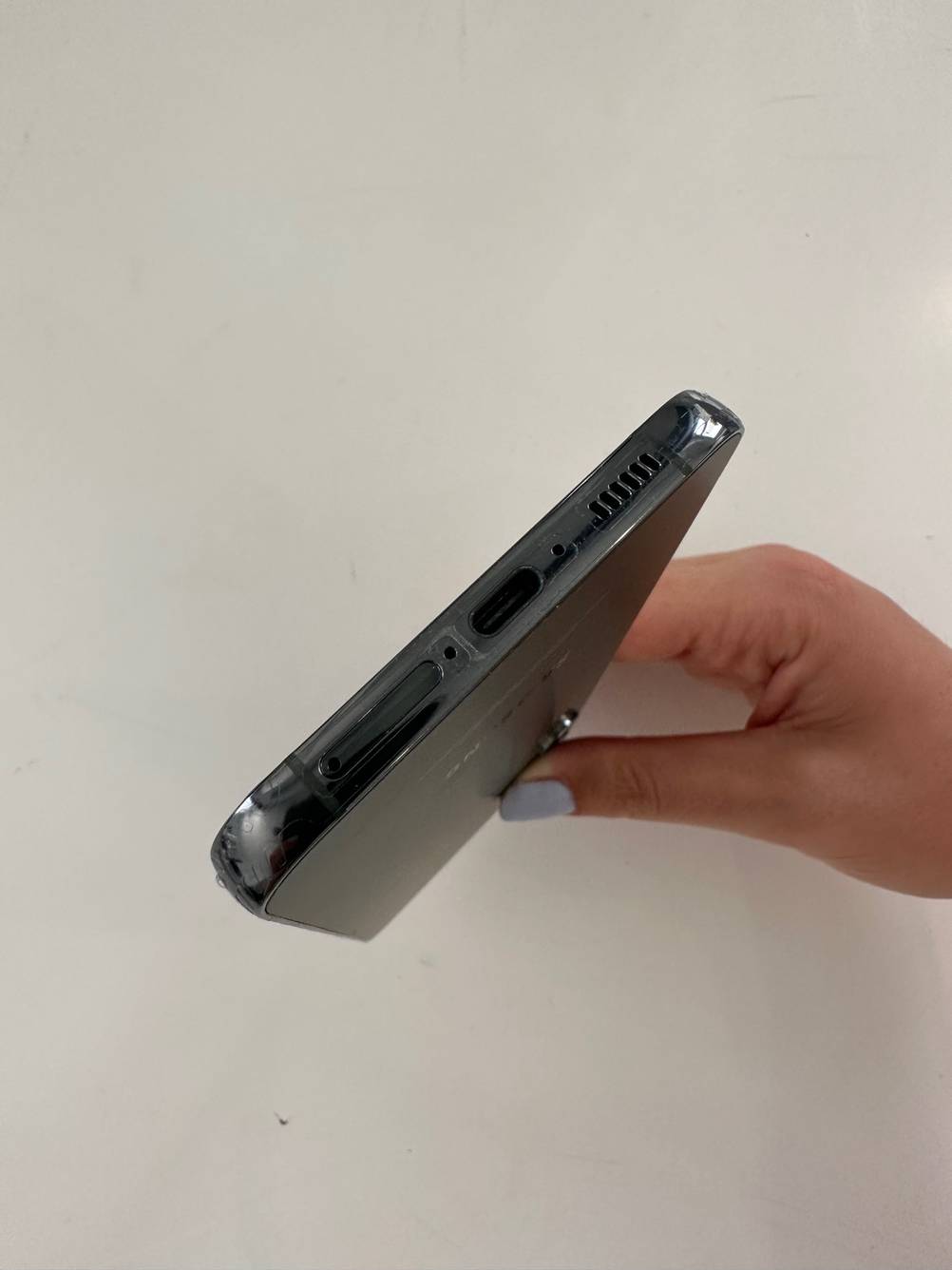 Eine Hand hält ein getestetes Samsung Smartphone mit Blick auf die Ladebuchse.