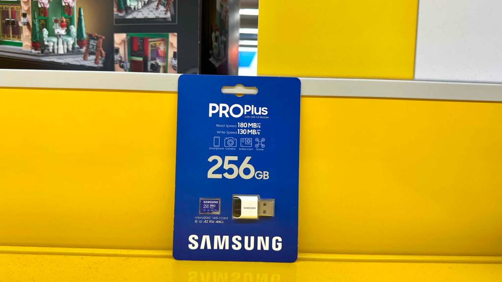 Eine getestete SDXC-256GB lehnt im Blister verpackt an eine gelbe Regalwand.