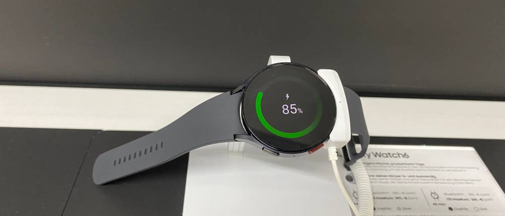 Samsung-Smartwatch-Test: eingeschaltete schwarze Samsung-Smartwatch mit Akkustandanzeige, die im Verkaufsbereich ausliegt