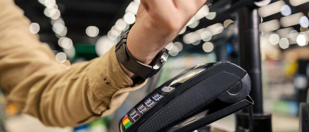 Samsung-Smartwatch-Test: Nahaufnahme des Arms einer Person, die im Supermarkt an einer Selbstbedienungskasse mit einer Smartwatch bezahlt
