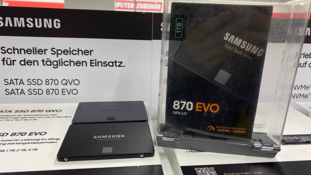 Eine Samsung-SSD im Test auf einer Infotafel, daneben eine Originalverpackung.
