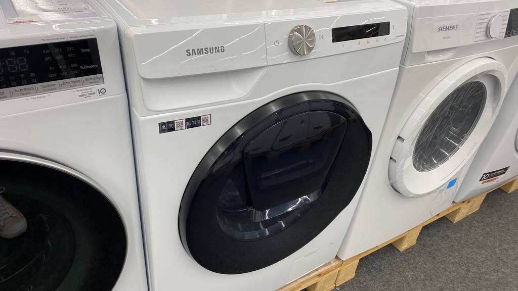 Im Test: Ein Samsung Waschtrockner steht neben anderen Marken auf Paletten.