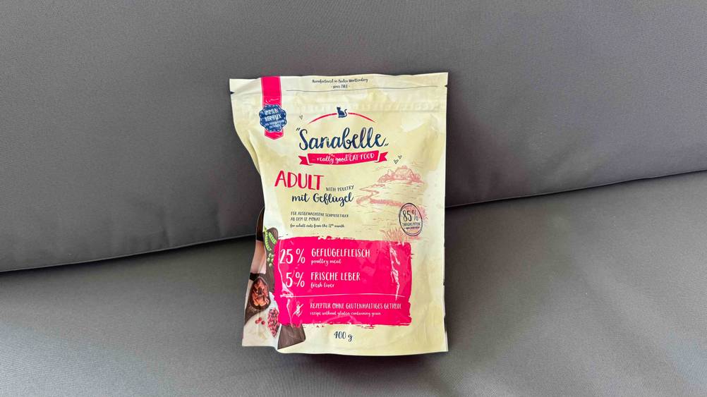 Eine Packung des getesteten Sanabelle-Trockenfutters auf einem grauen Polster liegend.