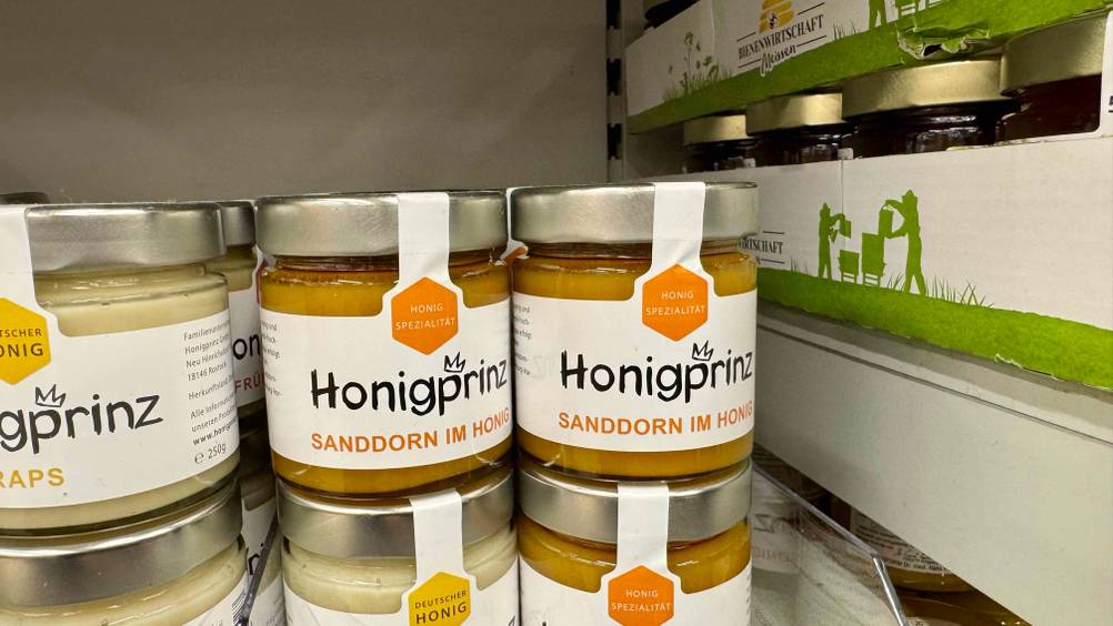 Mehrere Gläser des Sanddorn-Honigs im Test in einem Verkaufsregal neben andere Produkten.