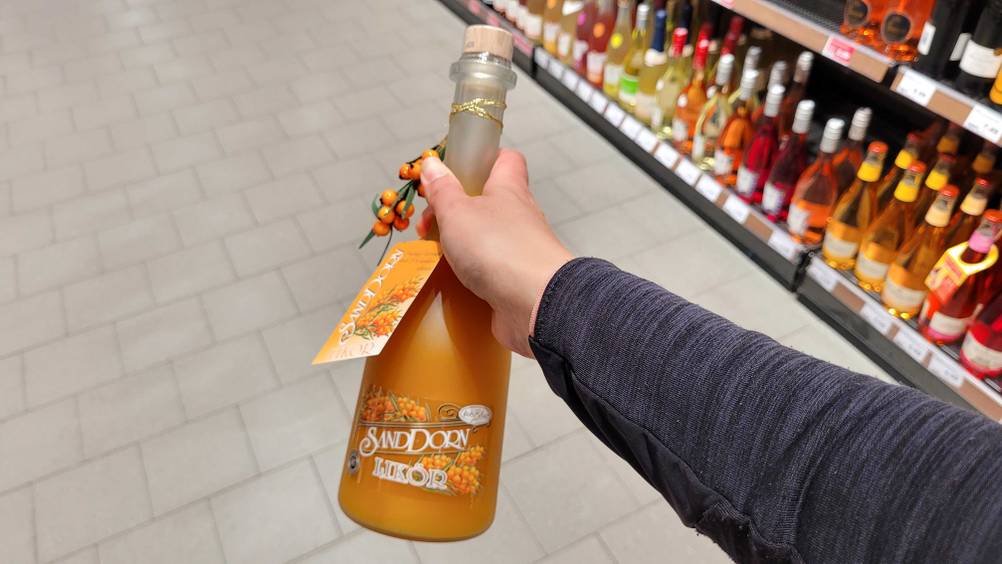 Eine Hand hält eine Flasche des getesteten Sanddornlikörs.