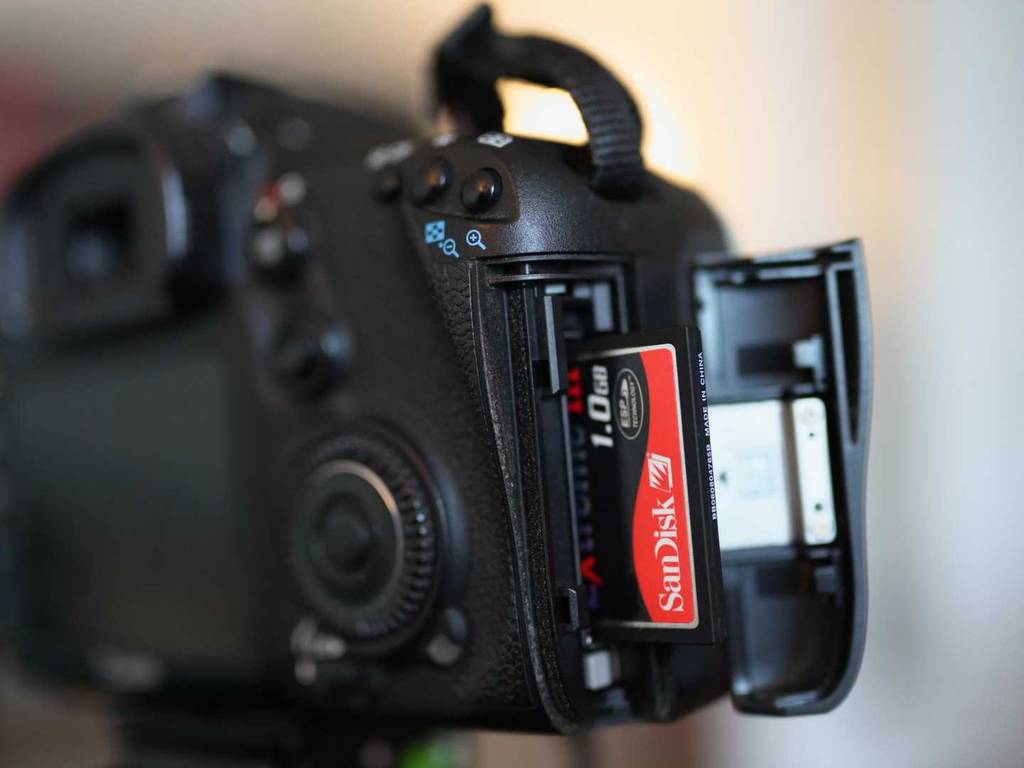 CF-Karten-Test: Nahaufnahme einer SanDisk 1.0 GB Karte, die halb eingeschoben im geöffneten Fach einer Digitalkamera steckt.