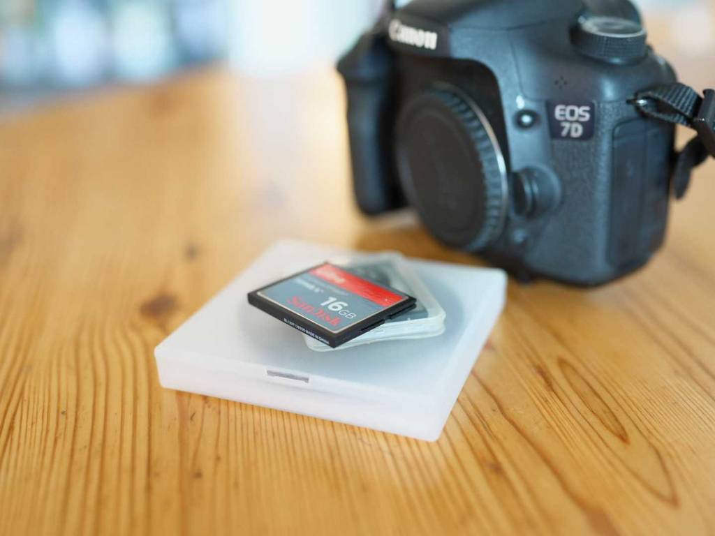 Eine (Compact-Flash 16 GB) CF-Karte im Test liegt auf seiner Aufbewahrungsbox vor einer Canon EOS 7D.