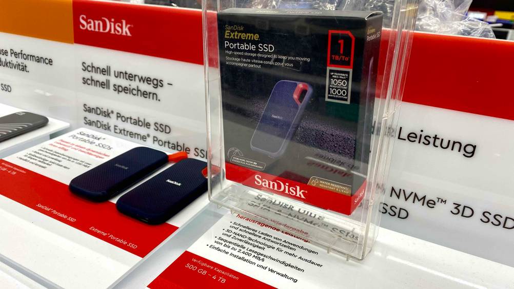 SSD (1TB) getestet: Ein Produkt in seiner Originalverpackung in einer transparenten Box, im Hintergrund eine Infotafel.