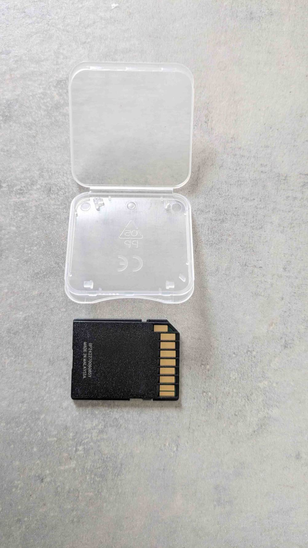 Neben der Plastikhülle liegt die getestete SanDisk-SSD mit der Rückseite nach oben.