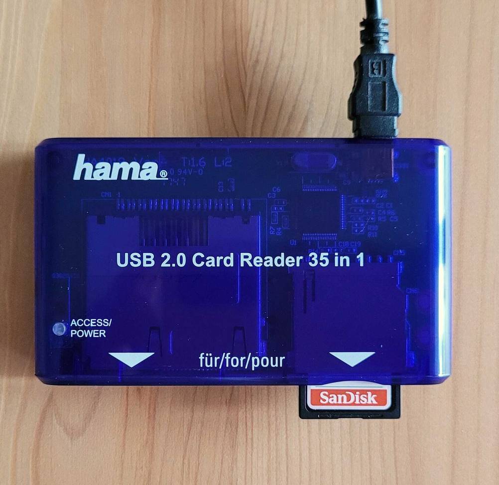 Eine getestete Speicherkarte in einem blauen Hama USB 2.0 Card Reader, der auf einer hellen Holzoberfläche steht.