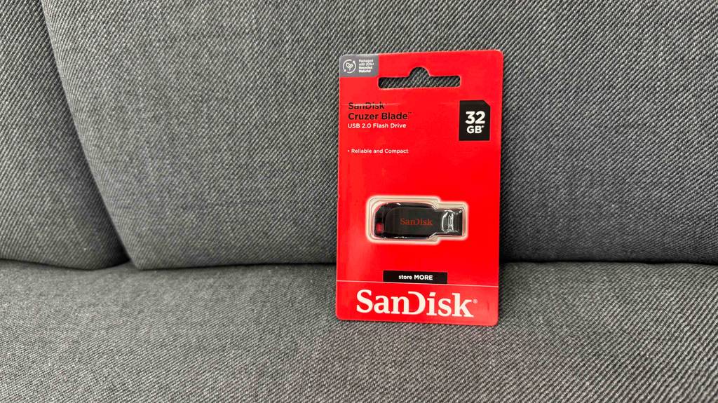 Getestet: Ein USB-Stick mit 32 GB Speicherplatz steht in seiner roten Originalverpackung auf einem grauen Sofa.