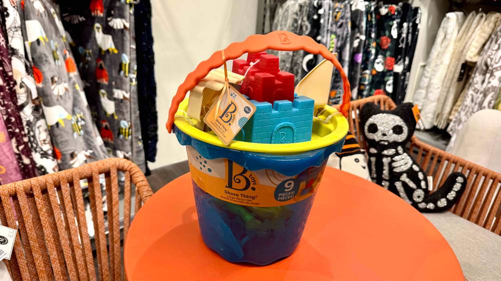 Sandkasten-Spielzeug im Test: Der Eimer mit dem Spielzeug auf einer orangenen Fläche.