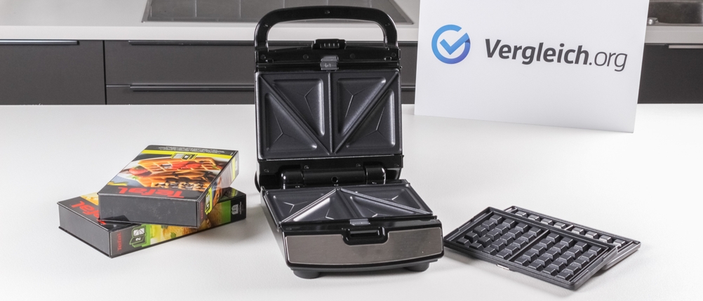 Ein getesteter Sandwichmaker von Tefal steht zusammen mit verschiedenem Zubehör auf einer hellen Arbeitsfläche.