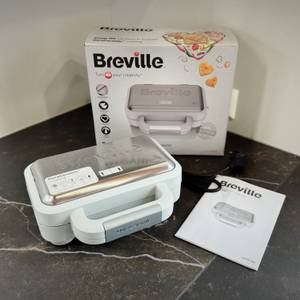 Der getestete Sandwichmaker von Breville steht mit der Verpackung und der Bedienungsanleitung auf einer Arbeitsfläche.