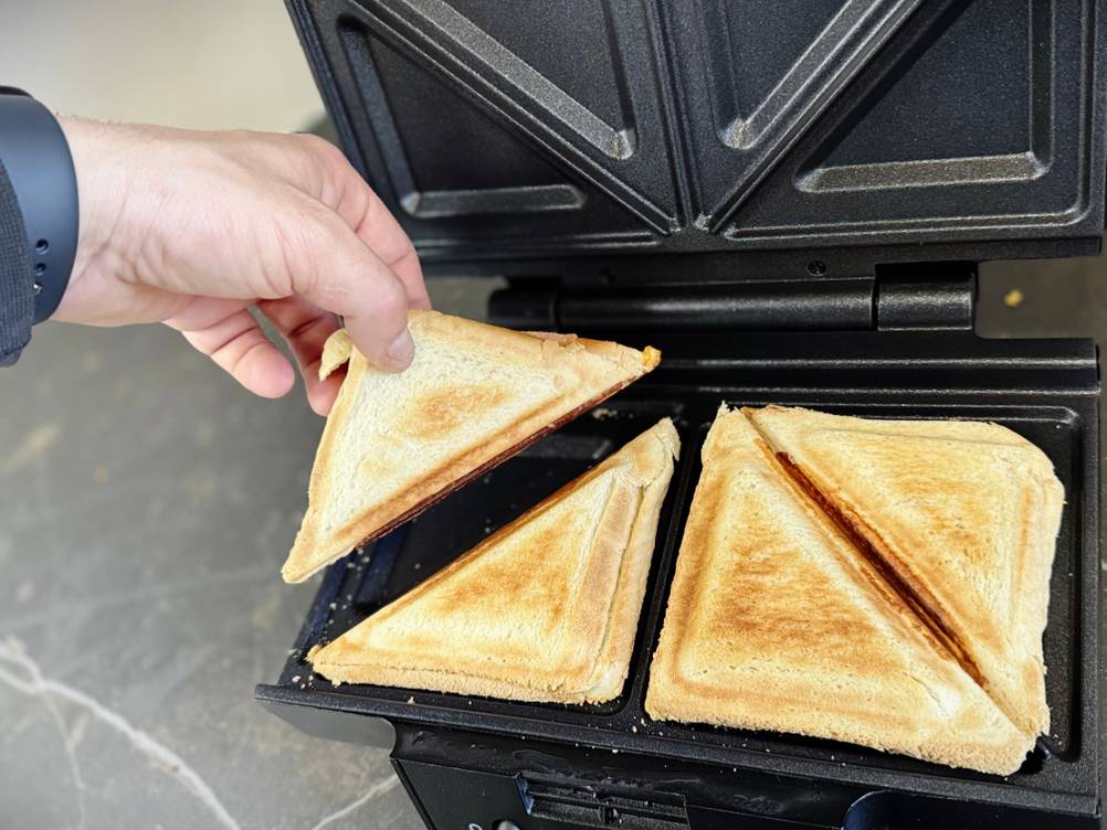 Eine Person nimmt ein halbes Sandwich aus dem getesteten Sandwichmaker von Krups.