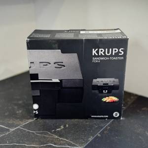 Der getestete Sandwichmaker von Krups steht verpackt auf einer dunklen Arbeitsfläche.