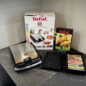 Der getestete Sandwichmaker von Tefal steht mit dem Zubehör auf einer Arbeitsfläche.