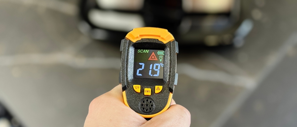 Test verschiedener Sandwichmaker: Eine Person misst mit einem Laser-Thermometer die Temperatur des Griffs vom Tefal-Sandwichmaker.