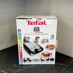 Der getestete Sandwichmaker von Tefal steht verpackt auf einer dunklen Arbeitsfläche.