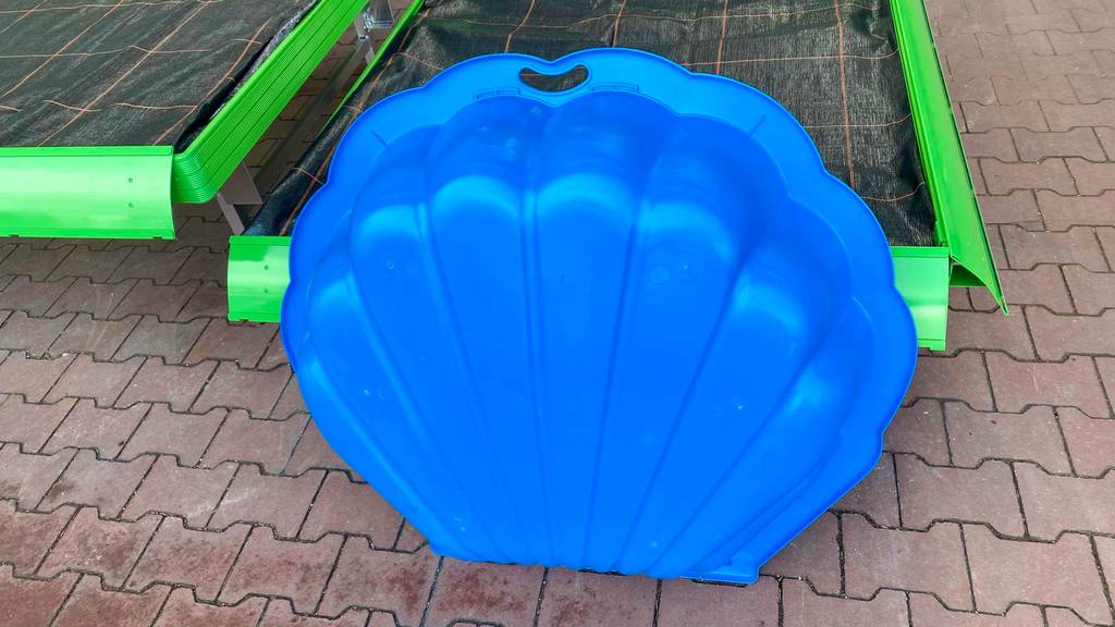 Getestet: Unterseite von einem Sandkasten aus Plastik, der hochkant an ein großes Beet lehnt.