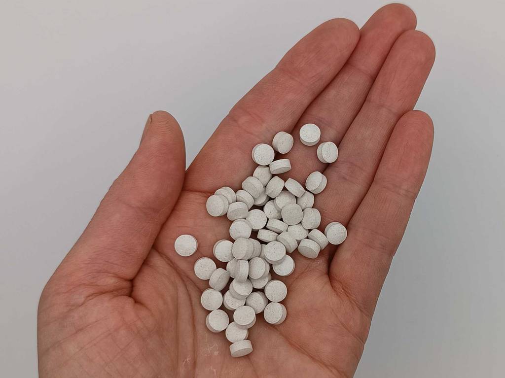 Im Test: Mönchspfeffer in Form von hellen, runden Tabletten liegt auf einer Hand.
