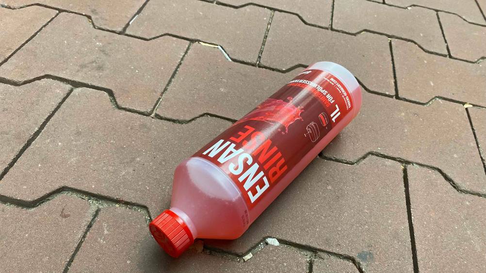 Auf dem Boden liegt eine Kunststoffflasche mit getesteter Sanitärflüssigkeit.