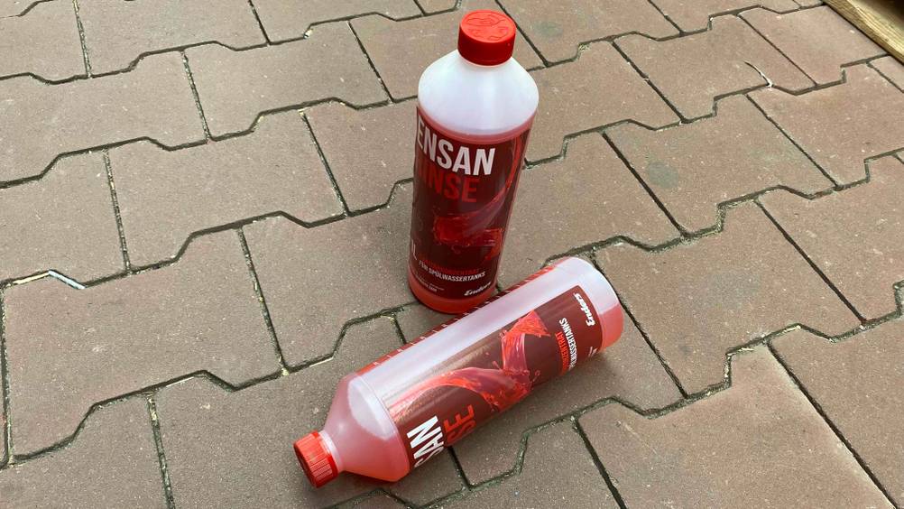Zwei Flaschen mit getesteter Sanitärflüssigkeit befinden sich auf dem Boden. 