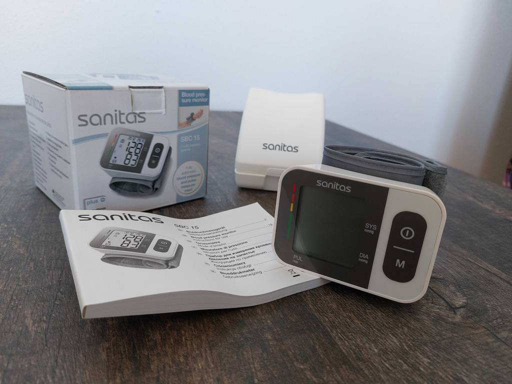 Sanitas Blutdruckmessgerät getestet: Komplettansicht mit Gerät, Aufbewahrungsbox, Originalverpackung und Bedienungsanleitung.