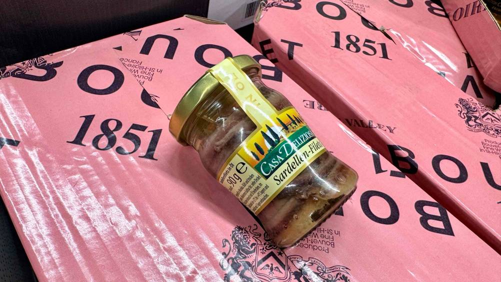 Sardellenfilet im Test: Ein Glas liegt auf rosa Kartons.