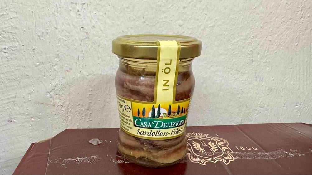 Vor einer hellen Wand steht ein Glas der getesteten Sardellenfilets.