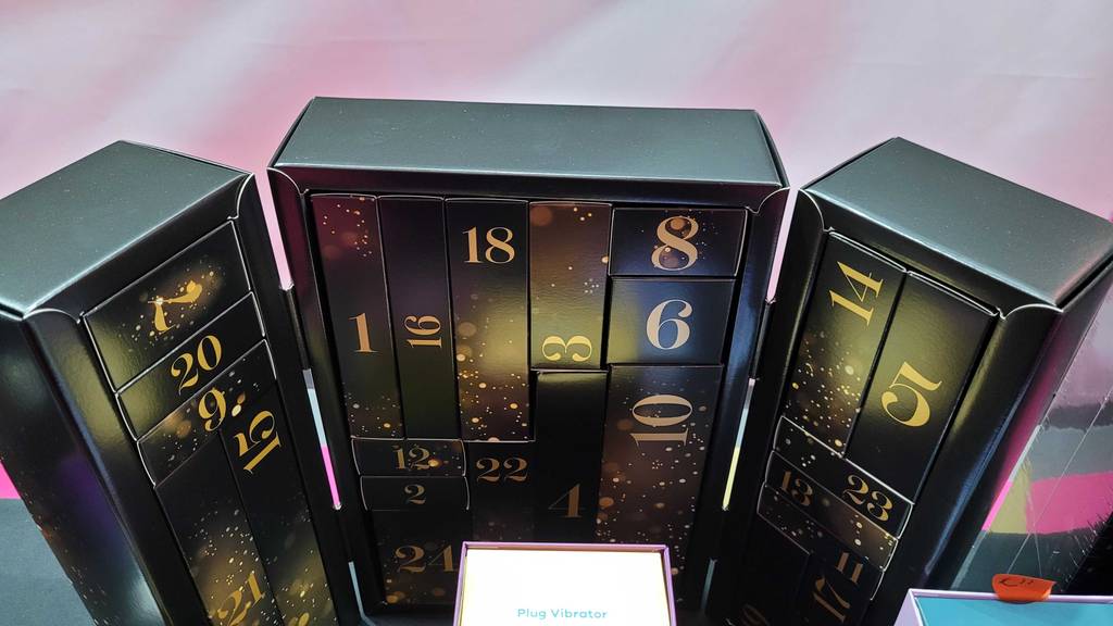 Gesamtansicht von oben eines Erotik-Adventskalenders im Test: schwarzer Kalender mit goldenen Ziffern und unterschiedlich großen Fächern.