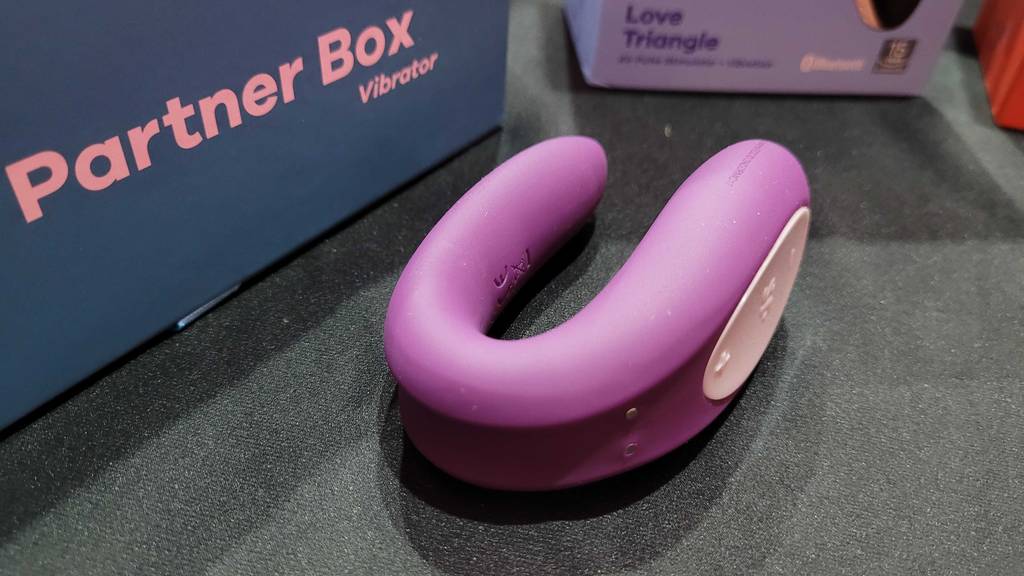 Paarvibrator-Test: auf einem schwarzen Untergrund liegen ein rosa, gebogener Vibrator der Partner Box von Satisfyer.