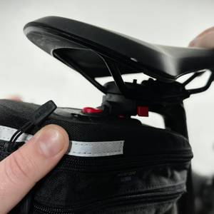 Eine Person befestigt die KLICKfix Micro 200 Satteltasche mithilfe des Klicksystems unter dem Sattel. Die Verriegelung ist sichtbar.