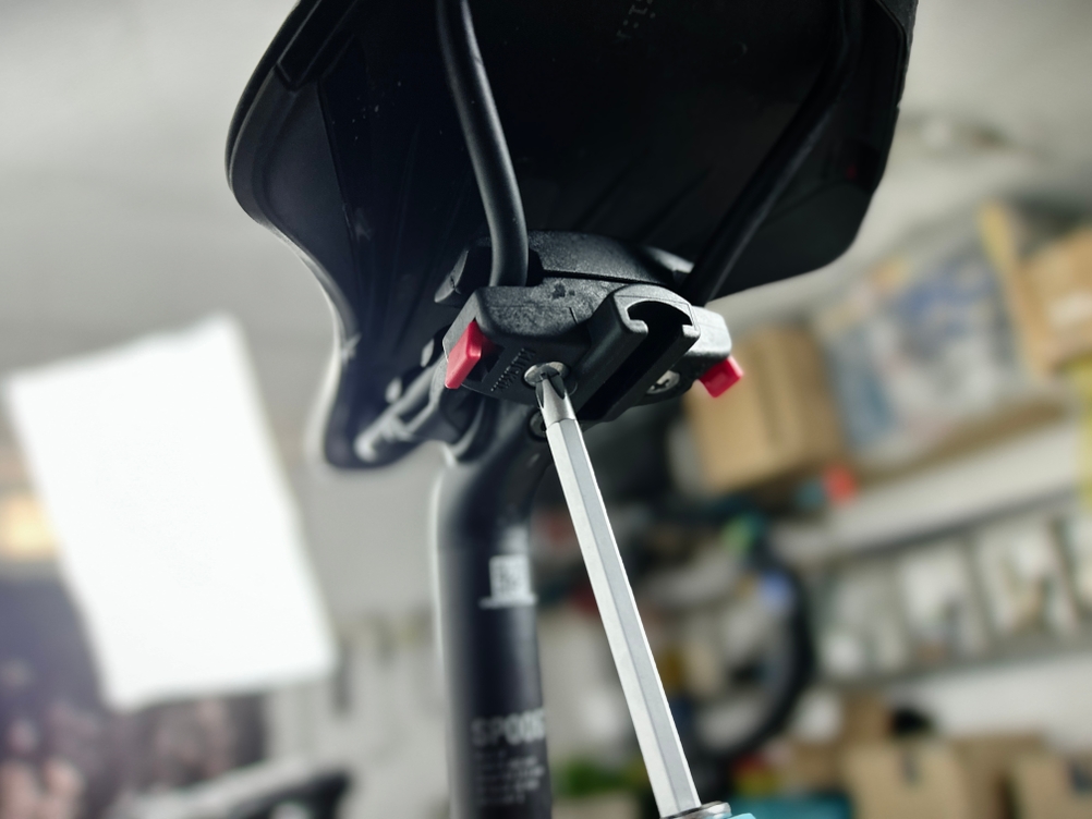 Ein Schraubendreher wird genutzt, um den KLICKfix-Adapter an der Sattelstrebe zu befestigen. Die Montage ist im Gange.