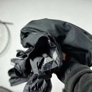 Eine Person hält eine gefaltete Regenjacke, die in die KLICKfix Micro 200 Satteltasche passt.