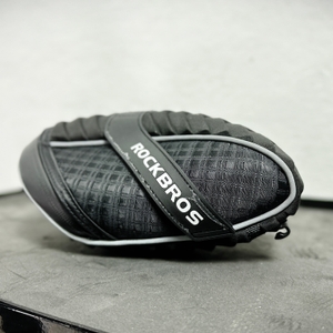 Seitenansicht der Rockbros C16-BK Satteltasche, die auf einer Oberfläche liegt. Das Design mit reflektierenden Elementen ist gut erkennbar.