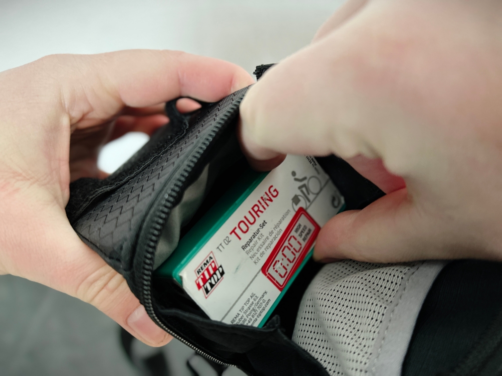 Eine Hand greift in die Satteltasche von Vaude. Darin ist ein Reifenflickset verstaut.