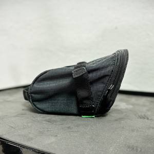 Seitenansicht der Vaude Race Light Satteltasche auf einer Oberfläche. Die kompakte Größe und das dezente Design sind gut erkennbar.