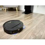 Ein schwarzer Staub-Wisch-Roboter fährt über einen Laminatboden.