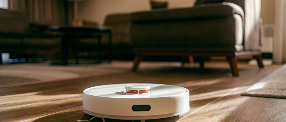 Saug-Wisch-Roboter im Test: weißer Saug-Wisch-Roboter saugt in einem Wohnzimmer mit Holzboden.