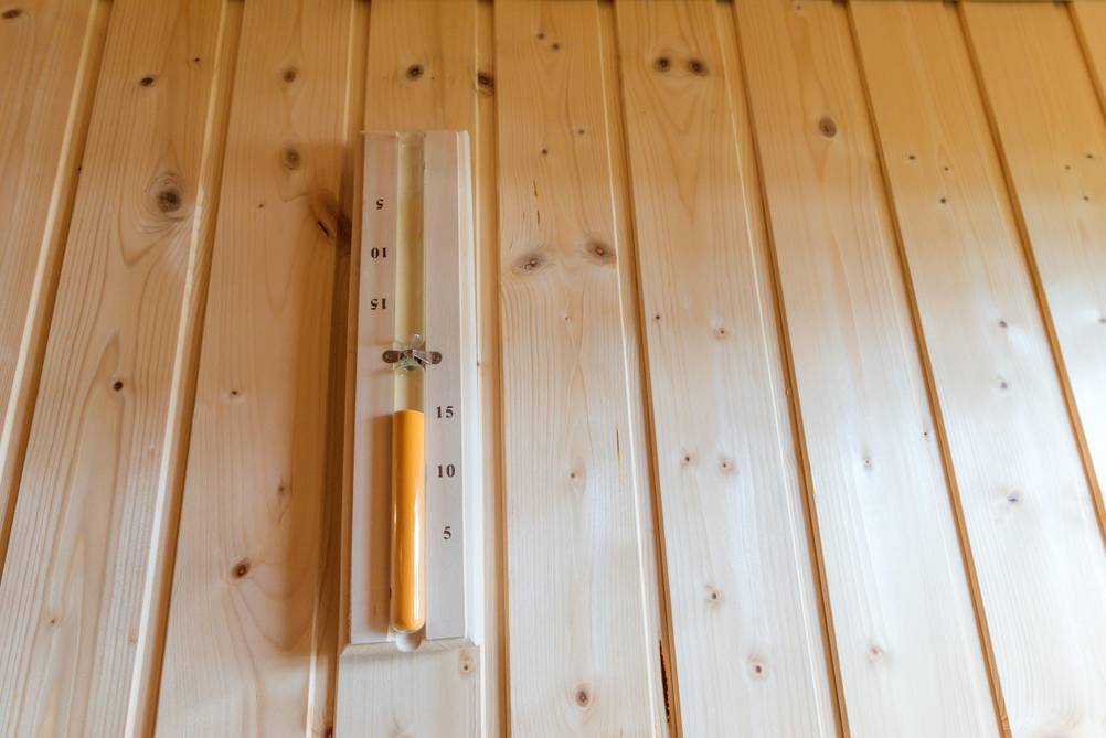 Sauna-Sanduhren im Test: Eine Holz-Saunauhr mit orangefarbigem Sand auf einer Holzwand.