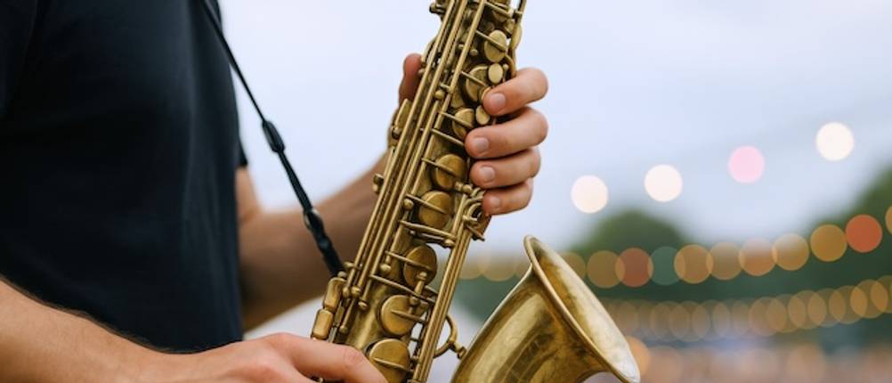 Saxophongurt im Test: Nahaufnahme von Händen, die auf einem Saxophon spielen, das von einem Saxophongurt gehalten wird.