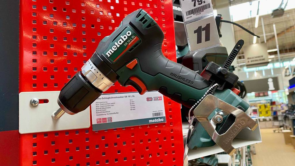Ein schwarz-grüner Metabo-Akkuschrauber im Test ist an einer roten Ausstellungswand im Verkaufsbereich befestigt.